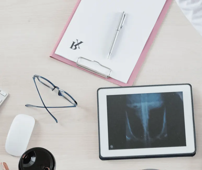 Desk with a tablet showing an X-ray, glasses and notes